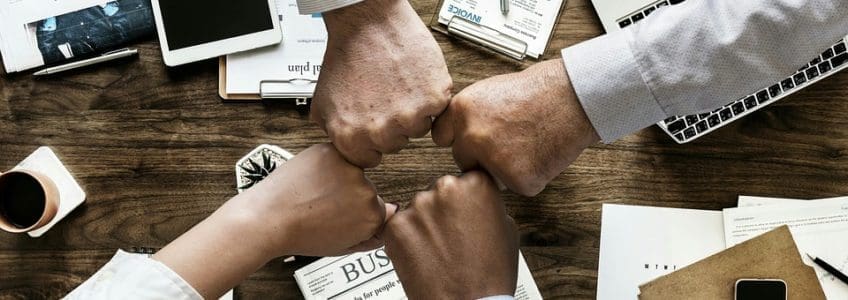 four people fist bump over desk