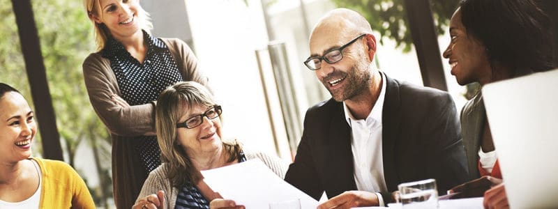 five smiling people review paperwork