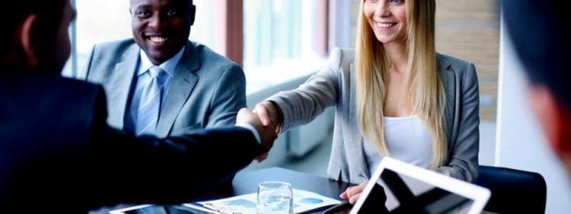 businesspeople shake hands across a table