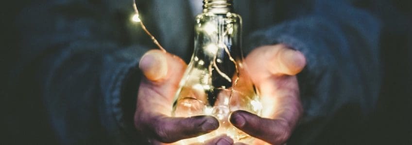 person holds a lightbulb with fairy lights inside