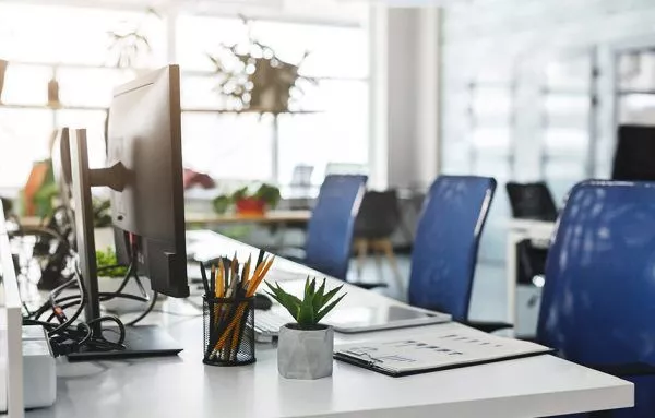 three empty blue desk chairs facing toward computers